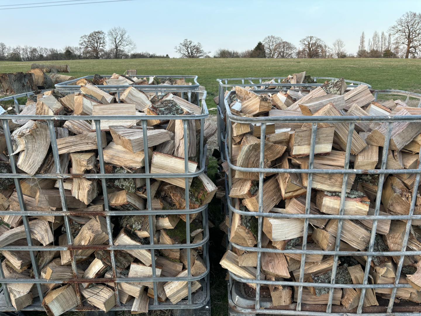 Two metal crates of split seasoned logs ready for collection